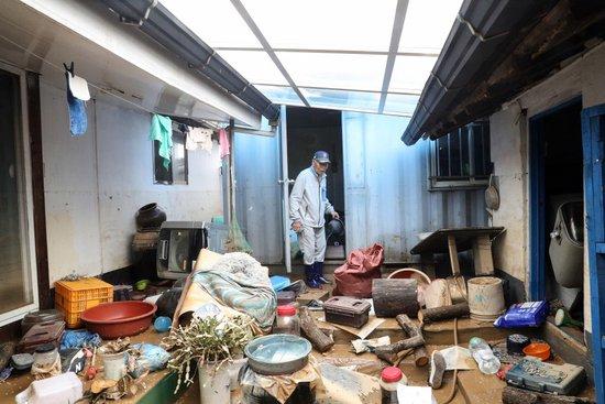 当地时间2025年7月18日，韩国忠清南道礼山郡，一名居民查看被暴雨损毁的房屋。视觉中国 图
